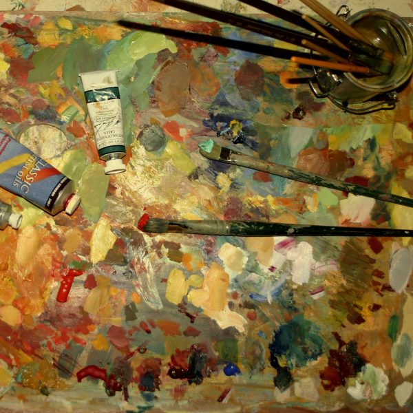 oil painting palette on wood palette with brushes and tubes of paint.